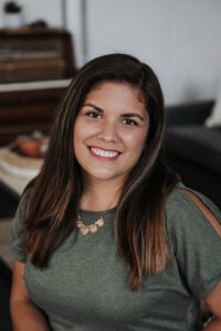 Headshot of Jess Galván, a Latina woman with long hair wearing a blouse and necklace