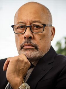 African American man with glasses, bald with a graying mustache and short beard, wearing a suit and looking serious